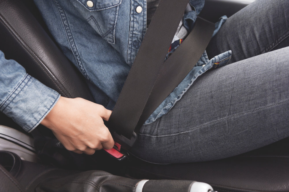 Female hands fasten the seat belt in the car. Conception of safe driving