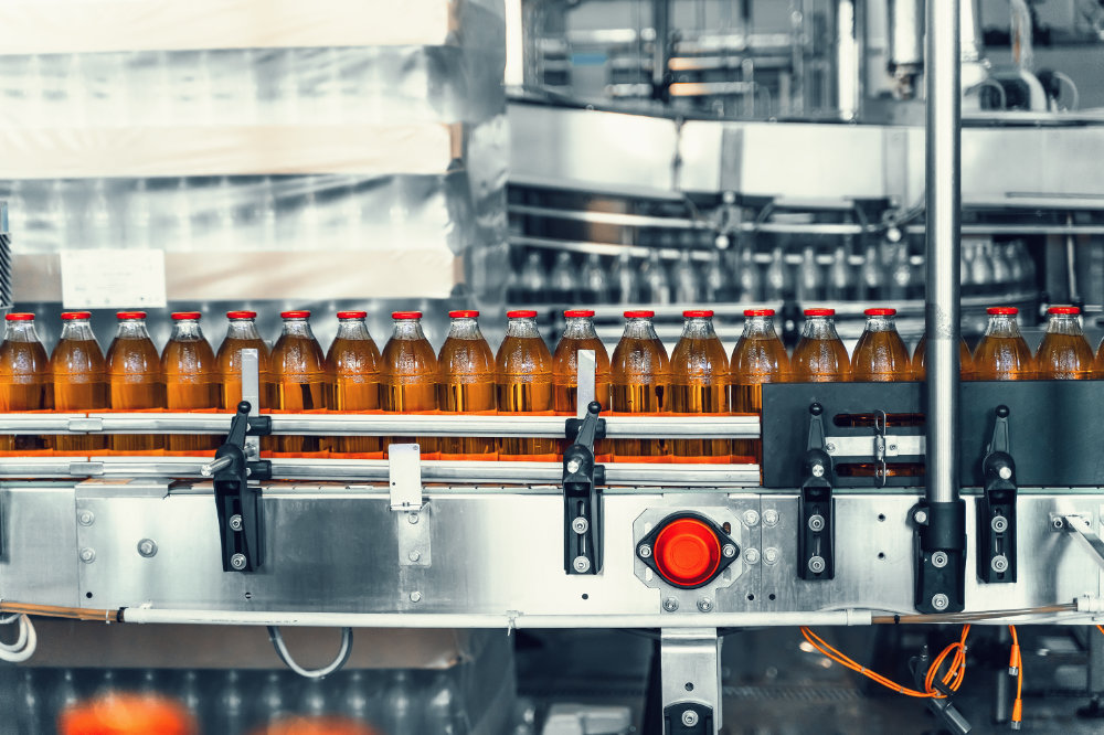 Conveyor belt, juice in glass bottles in automated machine equipment on beverage factory, close up