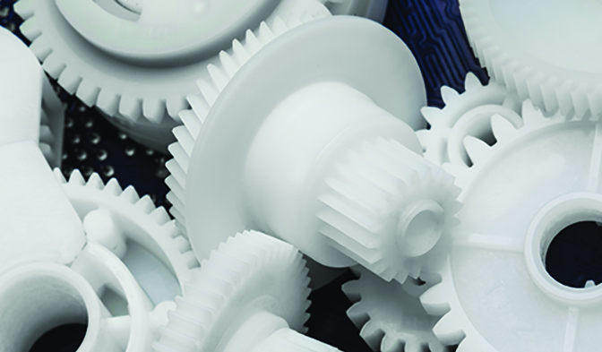 A close-up black and white photograph depicting a pile of plastic gears