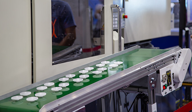 a conveyor belt with white molding caps on it