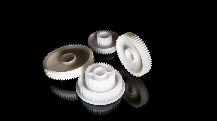 a zoomed in image of a group of white gears on top of a black reflective surface and background