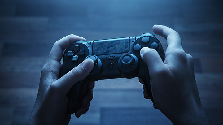 a zoomed in image of two hands holding a console game controller to play a video game