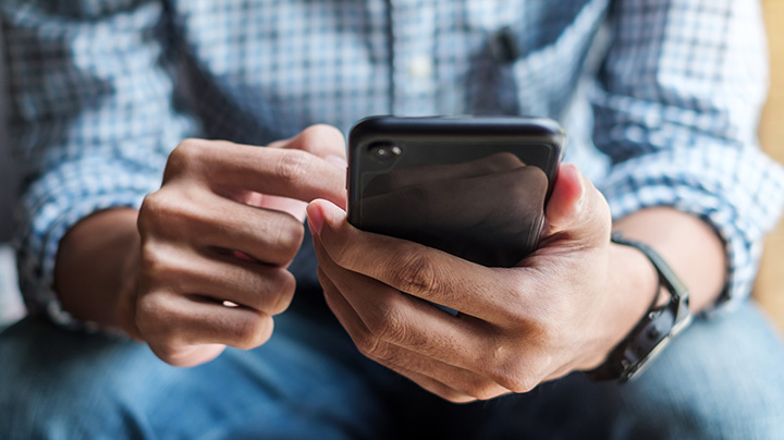 a zoomed in cropped image of a man browsing content on his smart phone