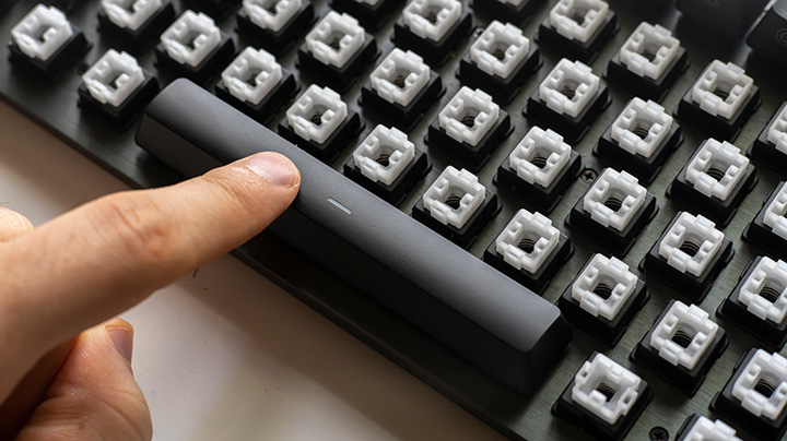 A zoomed in image of a finger pressing a keyboard with the key caps removed