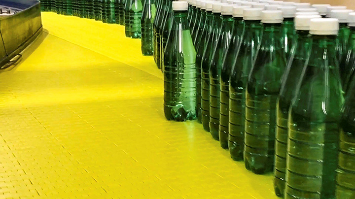 Factory production line with green bottles on yellow conveyor belt