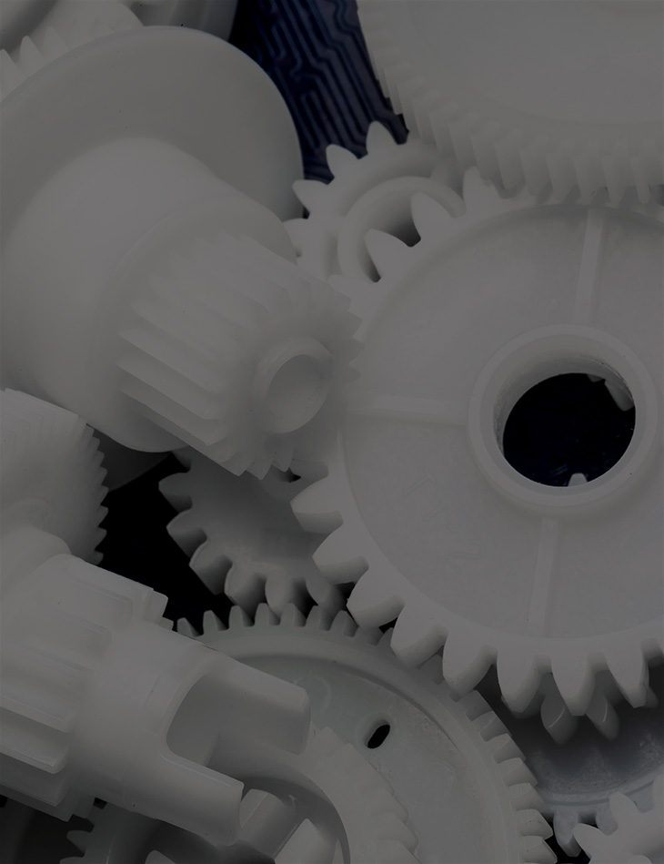 A close-up black and white photograph depicting a pile of plastic gears