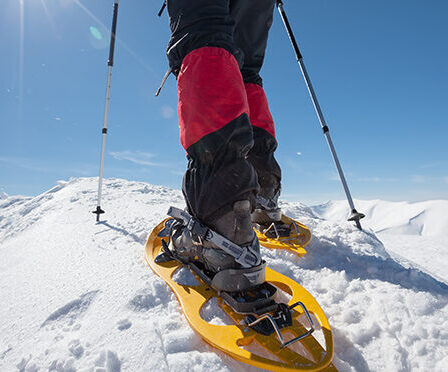 Hiker snowshoeing in winter mountains during sunny day