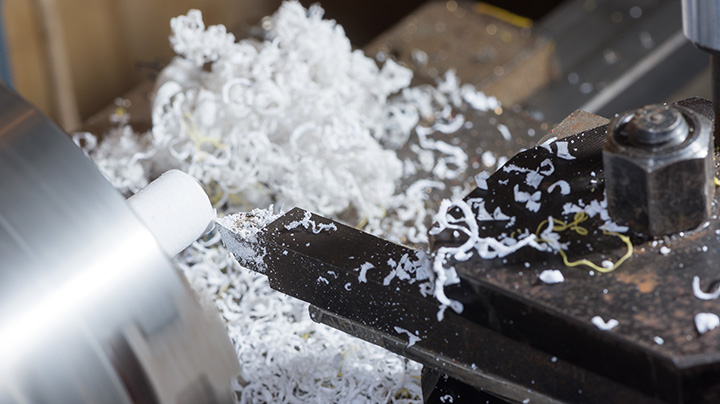 a closeup of a precision cutting machine over a pile of material shavings